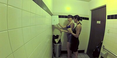 Two bitches are in the public bathroom, licking one another