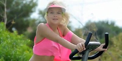 Petite blonde teen rides a stationary bike outdoors while being totally naked