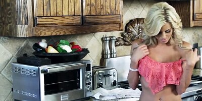 A blonde is naked in the kitchen and she is massaging her wet pussy